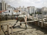 Palestinian worker flattens cement on the roof of a building under construction in Gaza