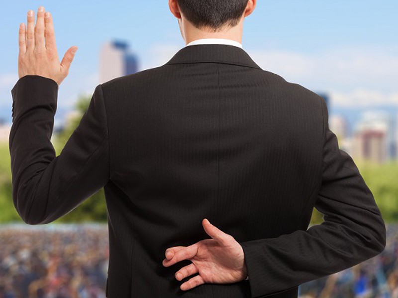 Politician swearing an oath with fingers crossed behind back