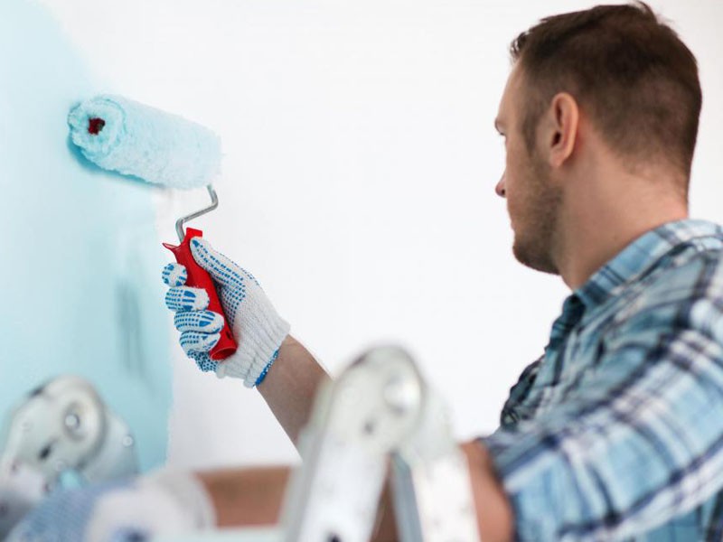 man-with-roller-painting-wall-blue