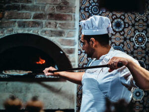 Chef is putting pizza to the oven